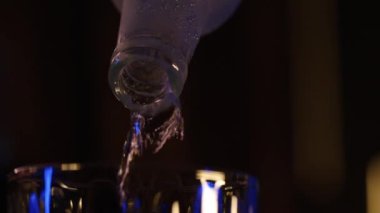 Alkol bir bardağa şişeden çıkan insanlarla doldurulur. Yakın çekim, döndürülmüş nesne