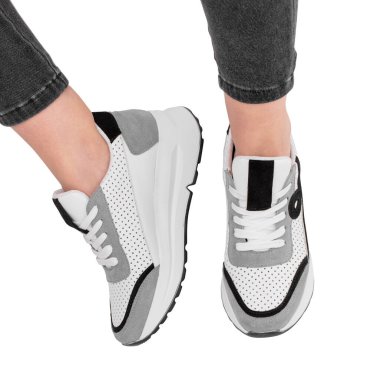 Beyaz arka planda şık spor ayakkabılı kadın bacakları.