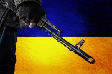 Ukrayna bayrağının arka planında makineli tüfeği olan Ukraynalı toprağını savunmaya hazır. Ukrayna 'da savaş çatışması