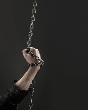 Siyah arka planda demir zincirlerle birbirine dolanmış eller. Kavram