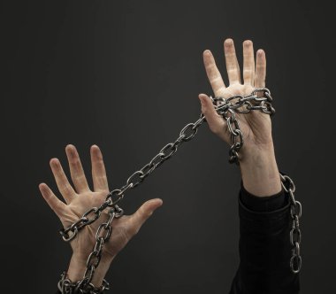 Siyah arka planda demir zincirlerle birbirine dolanmış eller. Kavram