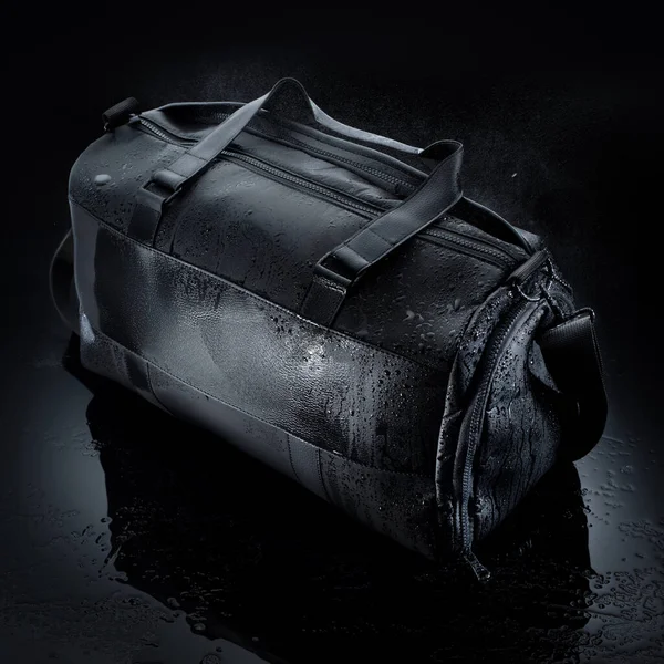 黒の背景に水滴や水のスプラッシュと防水スポーツバッグ — ストック写真