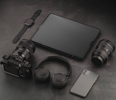 Aygıt modelleme şablonu. Karanlık bir yapısal arka planda video aksesuarları. Tablet, kulaklık, telefon, lens, video kamera ve saat
