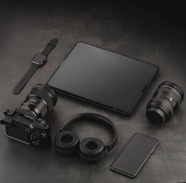 Devices mockup template. Video accessories on a dark structural background. Tablet, playback monitor, memory card holder, lens, video camera and watch