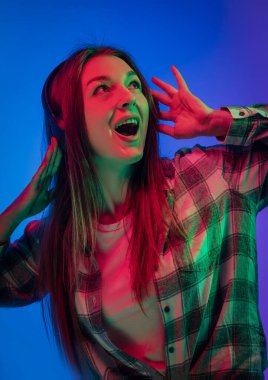 Çok renkli arka planda, neon ışıklarda genç duygusal kadın portreleri. Zevkle ve kulaklıkla müzik dinlemek. Faiziyle bakıyor, bardakları ayarlıyor. Broşür Posteri Afişi