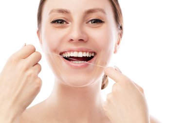 Gülümseyen kadın diş ipi kullanıyor ve izole edilmiş beyaz arka planda duran mükemmel dişlerle ilgileniyor. Diş ipi..