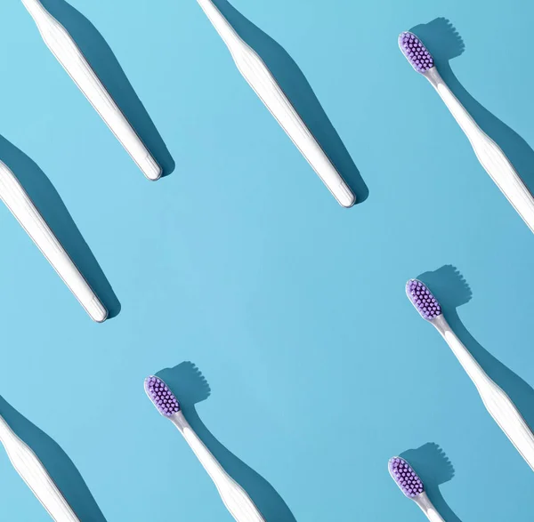 Toothbrushes pattern on a blue background. The concept of daily oral care. Advertising poster concept.