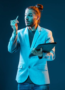 Koyu mavi arka planda elektronik tablet ve kalemle duygusal genç ve yakışıklı bir tasarımcı.