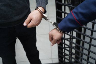 Bir polis memuru şüpheliyi kelepçeler.