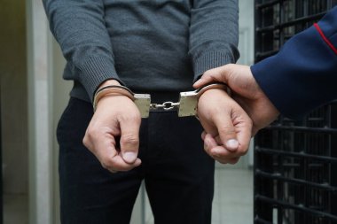 Bir polis memuru şüpheliyi kelepçeler.