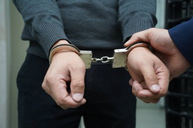Bir polis memuru şüpheliyi kelepçeler.