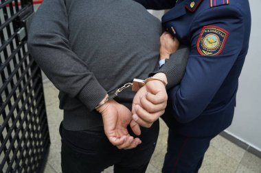 Bir polis memuru şüpheliyi kelepçeler.