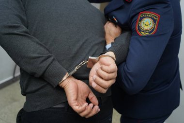 Bir polis memuru şüpheliyi kelepçeler.