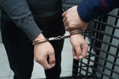 Bir polis memuru şüpheliyi kelepçeler.