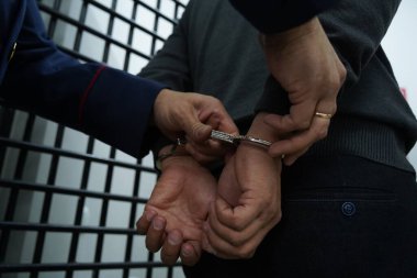 Bir polis memuru şüpheliyi kelepçeler.