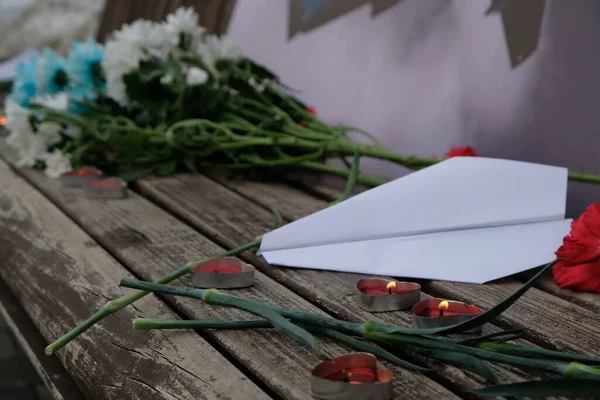 Kerzen Ein Papierflugzeug Und Blumen Auf Einer Bank Zum Gedenken — Stockfoto