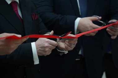 Takım elbiseli insanlar açılışta kırmızı kurdeleyi kestiler.