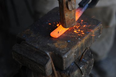 Almaty, Kazakhstan - 09.24.2015 : A blacksmith makes a metal holder for knives and tools in the workshop.