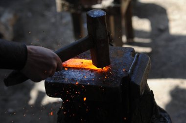 Almaty, Kazakhstan - 09.24.2015 : A blacksmith makes a metal holder for knives and tools in the workshop.