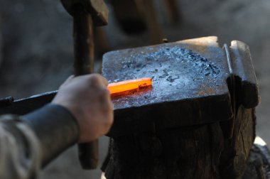 Almaty, Kazakhstan - 09.24.2015 : A blacksmith makes a metal holder for knives and tools in the workshop.