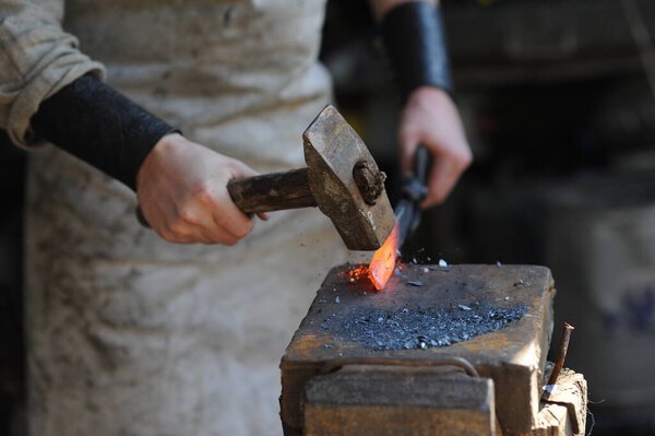 Almaty, Kazakhstan - 09.24.2015 : A blacksmith makes a metal holder for knives and tools in the workshop.