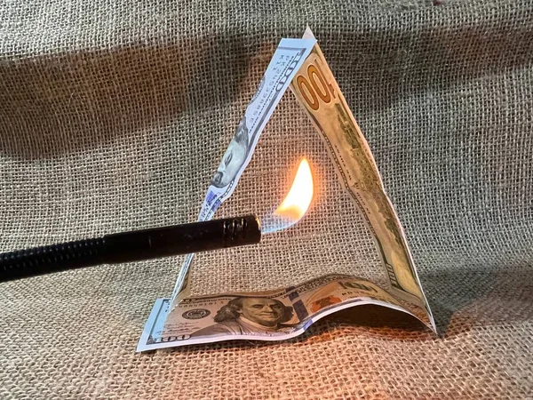 A lit fire from a gas burner and dollar bills on the table.