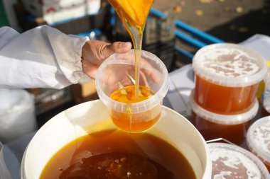 Satıcı marketteki bir konteynıra taze bal döker..