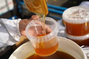 Satıcı marketteki bir konteynıra taze bal döker..