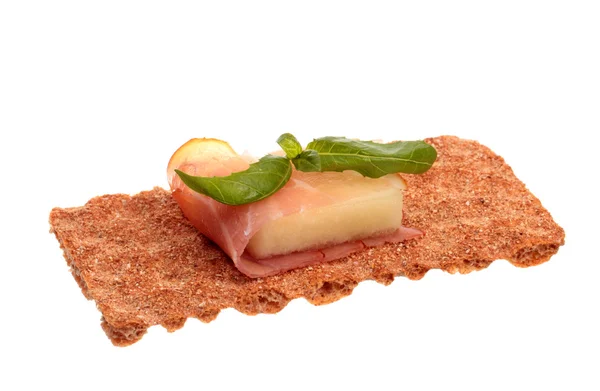 Parma ham with melon and basil on a rye crisp — Stock Photo, Image