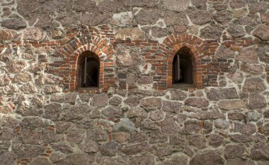 Arka planda iki penceresi olan eski taş duvar