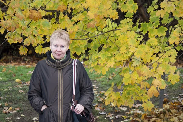 Donna matura vicino albero autunnale — Foto Stock