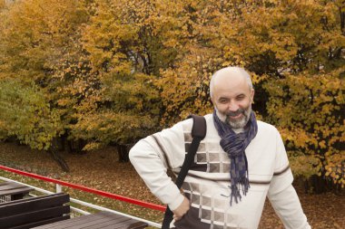 Orta yaşlı bir adam gözlerini kısarak gülümseyen