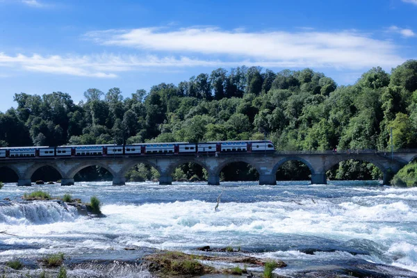 ニーホーゼン ラインの滝 スイス 2022年5月26日 ライン川を渡るライン川の鉄橋がヨーロッパ最大の滝の近くにあります 橋の上を電車が走っている — ストック写真