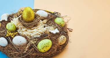 Yuvasında renkli yumurtalar olan Paskalya arkaplanı. Kopyalama alanı olan üst görünüm