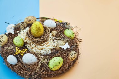 Yuvasında renkli yumurtalar olan Paskalya arkaplanı. Kopyalama alanı olan üst görünüm
