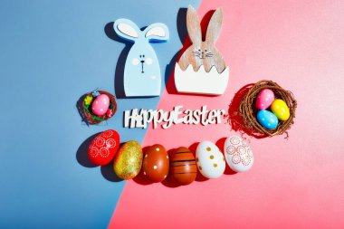 Mutlu Paskalya tatili kavramı. Düz renkli tavşan yumurtaları ofis masasındaki güzel gri-pembe kağıdın üzerine seriliyordu..