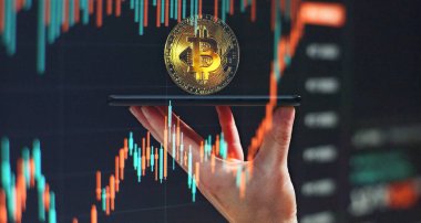 Smartphone with Bitcoin trading chart . Holding in hand a gold Bitcoin Cash coin. Trading on the cryptocurrency exchange.