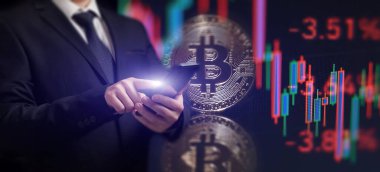 Bitcoin ticaret grafikli akıllı telefon. Elinde altın bir Bitcoin nakit para tutuyor. Kripto para değişimi ticareti..