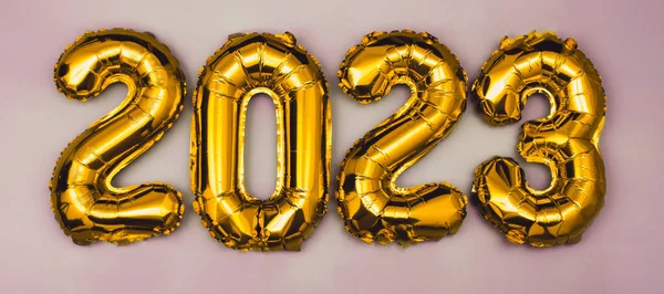 2023 golden foil balloons numbers,  stars confetti, ribbons and bokeh. Top horizontal view copy space new year and holiday concept.
