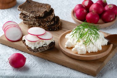 Ev yapımı çavdar ekmeği ahşap kesim tahtasında peynir ve turpla.