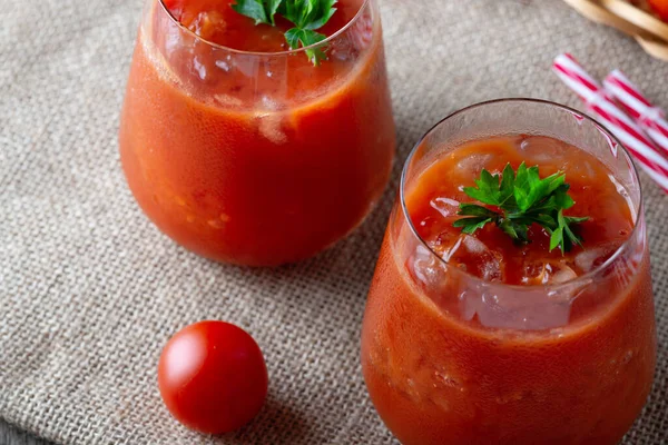 Томатный сок со льдом в стакане, петрушка и помидор на упаковке — стоковое фото