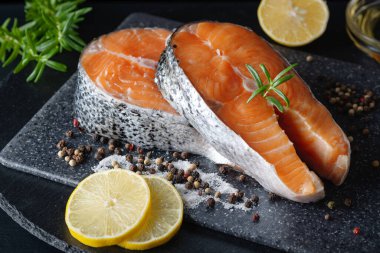 Lezzetli taze somon. Siyah bir masada limon, tuz ve baharat. Sağlıklı deniz ürünleri kavramı