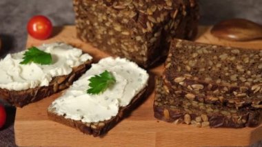 Çavdar ekmeği ahşap bir kesim tahtasının üzerinde peynir, ricotta ve otlarla.