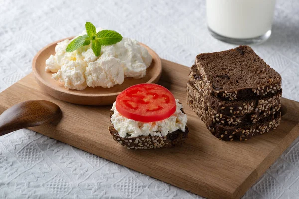 Кусочки ржаного хлеба с творогом и помидорами на деревянной тарелке — стоковое фото
