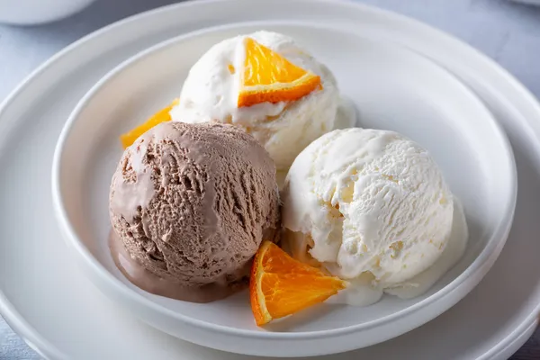 Ванильное и шоколадное мороженое с апельсиновыми ломтиками — стоковое фото
