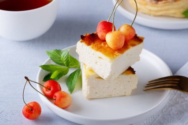 Süzme peynirli güveç ve ahşap ışıklı masada tatlı kiraz.. 