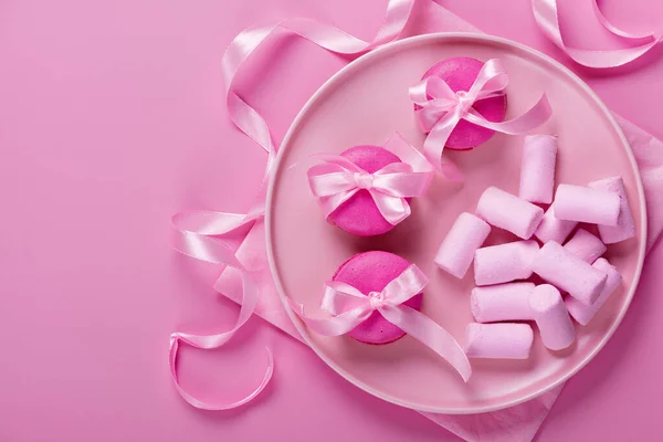 Pink macaroons and marshmallows on pink background. Sweet background. — Fotografia de Stock