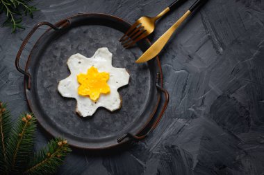 Eski bir tavada ev yapımı sahanda yumurta, gri bir arka plan. Yıldız şeklinde yumurta sarısı.