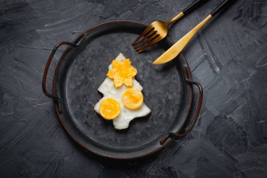 Eski bir tavada ev yapımı sahanda yumurta, gri bir arka plan..