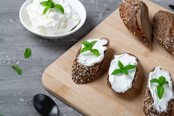 Pão caseiro em uma tábua de corte de madeira com queijo coalhado — Fotografia de Stock